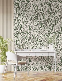 a white desk sitting in front of a wall with green leaves on it and a potted plant next to it