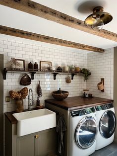 a washer and dryer in a small room with shelves on the wall above them