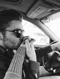 a man sitting in the driver's seat of a car talking on his cell phone