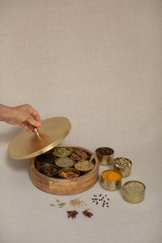 The Ayurvedic Spice Box, or Masala Dabba as it is more often called in India, is a high-quality replica of a classic Indian spice chest that comes with an outer container, seven smaller containers, and a miniature spoon. The Ayurvedic Spice Box or Masala Dabba is an ideal container for the most important spices used in Ayurvedic cooking; having them “at hand” (like paints on an artist's palette) makes it enjoyable and simple to experiment with new Indian cuisines. The Indian masala dabba (where Indian Spice Dabba, Masala Dabba Boxes, Ceramic Spice Container, Indian Spice Container, Indian Masala Spices, Indian Spices Photography, Spices Containers, Resin Photography, Ayurvedic Cooking