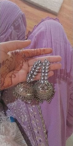 a woman's hand with henna and rings on her fingers, in front of a mirror