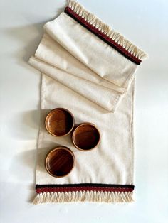 three wooden bowls sitting on top of a white cloth covered placemat with red trim