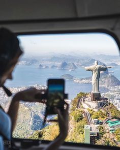 a woman taking a photo of the statue of christ in rio