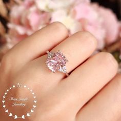 ''Hand made 3-carat eq. (8*10 mm) Cushion cut Fancy Pink diamond simulant engagement ring, with 3 diamond simulants on each side, set in white gold or rose gold plated sterling silver, discreetly adjustable band.'' See a video of this ring here: https://www.instagram.com/p/B9eMgMwlARE/ Unique on Etsy!  This is a stunning ring with a very pretty pastel pink centre stone, we're confident that this ring will make that perfect special gift. It has a marvellous and classic look that definitely stands August Moodboard, Pink Diamond Wedding Rings, Fancy Pink Diamond Ring, Pink Diamonds Engagement, Ring 3 Stone, Pink Diamond Engagement Ring