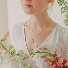 a woman holding a bouquet of flowers in front of her face and looking at the camera