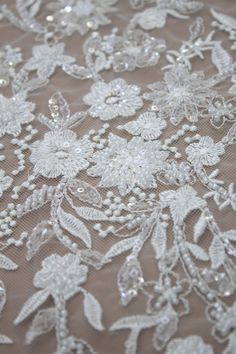 white lace with flowers and beads is shown on a tablecloth that has been embroidered onto it