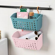 a blue and pink basket hanging on the wall next to a toilet paper dispenser