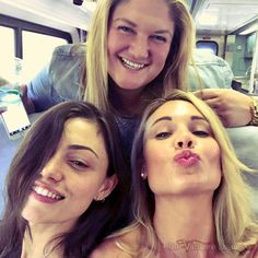 three beautiful women sitting next to each other on a train with their mouths open and tongue out