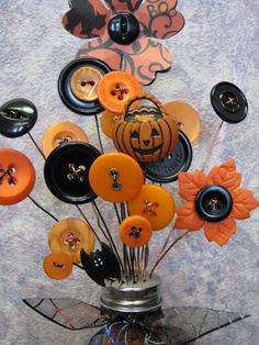 a vase filled with lots of orange and black buttons