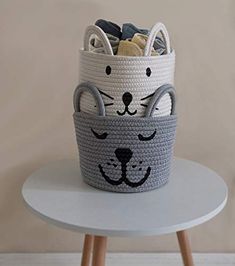 a cat basket sitting on top of a white table next to a wooden stool and wall