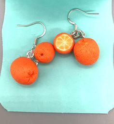 These unique artisan earrings are hand crafted using polymer clay.  Sweet juicy oranges dangle from silver toned earring hooks.  Why not fashionably show your love of oranges?!   Polymer clay is very lightweight and brightly colored.  They are sure to be your favorite pair of earrings! Earrings measure 3/4 inch tall by 3/4 inch wide. Orange Jewelry With Fruit Design For Gifts, Orange Fruit Design Jewelry For Gift, Orange Fruit Design Jewelry Gift, Unique Orange Nickel-free Jewelry, Orange Dangle Earrings Polymer Clay, Orange Dangle Polymer Clay Earrings, Orange Dangle Earrings In Polymer Clay, Orange Dangle Polymer Clay Jewelry, Orange Polymer Clay Dangle Earrings