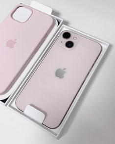 an open box with two pink iphones in it on a table next to each other