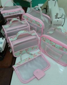 pink and white suitcases sitting on top of a table next to a sewing machine