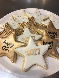 a white plate topped with cookies covered in gold and white frosted stars on top of a table