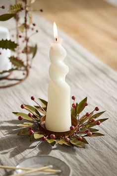 a white candle sitting on top of a table next to a silver plate and fork