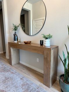 a wooden table sitting in front of a mirror next to a potted plant