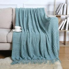 a blue blanket sitting on top of a couch next to a book shelf