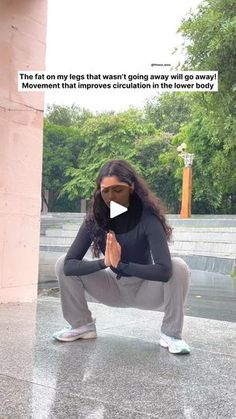 a woman kneeling down in front of a building with her hands clasped to her chest