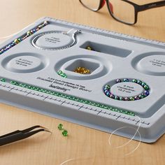 a pair of glasses sitting on top of a table next to a bead tray