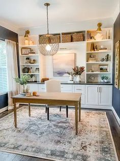 a dining room table and chairs in front of a large window with open shelving