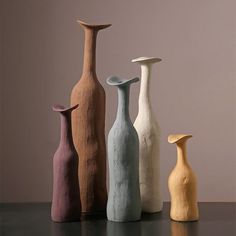 five different colored vases sitting on top of a table