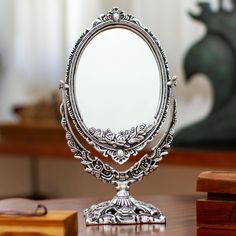 an ornate silver mirror sitting on top of a wooden table