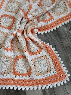 an orange and white crocheted blanket on the floor