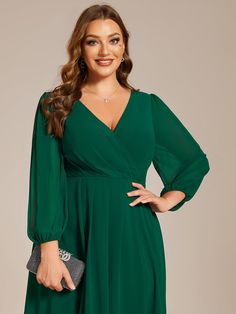 a woman wearing a green dress with long sleeves and a v - neckline is posing for the camera