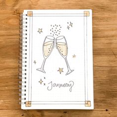 a spiral notebook with two glasses of champagne on the cover, and stars in the background