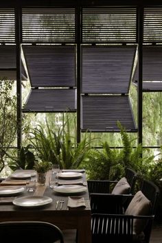 a dining room table set with plates and place settings in front of large windows that look out onto the outdoors