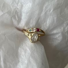 two different colored stones are sitting on top of a white piece of cloth, with one ring in the middle