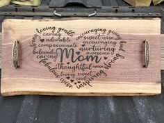 a wooden cutting board with writing on it that says mom and two knives in the shape of a heart