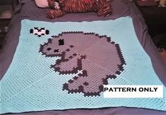 a crocheted elephant blanket on a bed with a teddy bear laying next to it