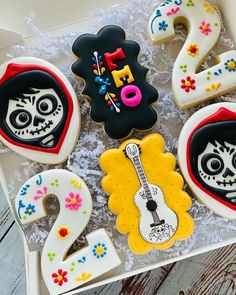 decorated sugar cookies in the shape of numbers and skulls are displayed on a white tray