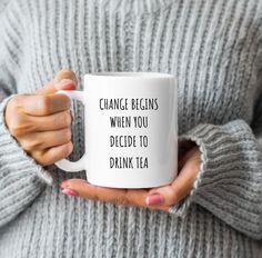 a woman holding a coffee mug that says, change begins when you decide to drink tea