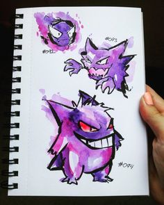 a hand holding a notebook with two drawings of pokemons on the pages and one has red eyes