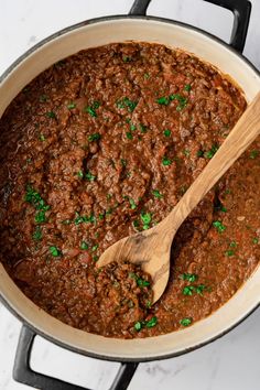 a wooden spoon in a pot filled with chili