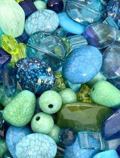 there are many different colored glass beads in this pile, including one blue and one green