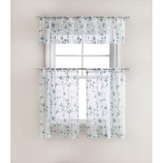 the window is decorated with blue and white floral curtains, which are hung above a bed