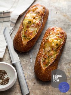 two baked egg boats sitting on top of a table next to a knife and bowl