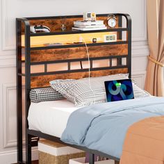 a bed with a laptop sitting on it's headboard next to a window