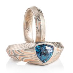 "* Price may vary depending on ring size, please inquire with us directly with your needed size for accurate pricing! This beautiful custom made Mokume Gane ring set features our Embers palette and a variation on our Twist Pattern, creating stars! Ring 1 features a modified cathedral style setting and beveled edge, showing off a lovely Alexandrite. Ring 2 also features a matching beveled edge. Both rings have an etched finish. Ring 1 -  Width Shown: 10mm tapered Size Shown: 6 Pattern: Twist/Star Palette: Embers Finish: Etched Profile: Beveled Stone: Approx. 9mm wide Alexandrite Setting: Customized Cathedral Ring 2 -  Width Shown: 4mm Size Shown: 5.25 Pattern: Twist/Star Palette: Embers Finish: Etched Profile: Beveled *Price does NOT include stones or setting fees* If you're interested in a Mokume Gane Ring, Stars Ring, Cathedral Ring, Celestial Ring, Twist Pattern, Mokume Gane, Custom Wedding Rings, Alexandrite Ring, Beveled Edge