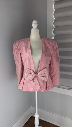 "Formal, fancy women's jacket. Pink brocade fabric is cotton polyester medium weight with acetate lining. Large shoulder pads, hook eye and snap front closure. Rhinestones on large front bow. Size 10 runs a bit small. 30\" waist, 18\" across back between armpits. 16\" across top of shoulders. 24\" length, 23\" sleeves. It is in perfect condition with no stains, spots, or tears. You may want to have it dry cleaned to freshen it up before wearing as this vintage jacket has been sitting in a closet Feminine Fitted Blazer For Parties, Pink Formal Winter Blazer, Pink Winter Formal Blazer, Winter Pink Formal Blazer, Formal Feminine Blazer, Pink Feminine Blazer For Formal Occasions, Pink Feminine Formal Blazer, Feminine Pink Outerwear For Evening, Fitted Feminine Formal Outerwear