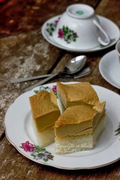 two pieces of cake sitting on top of a white plate next to cups and saucers