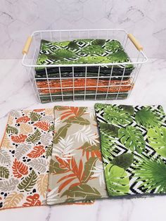 four placemats in different colors and patterns on a marble counter top with a wire basket