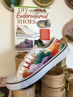 a pair of colorful shoes sitting on top of stacks of wooden baskets in front of wall