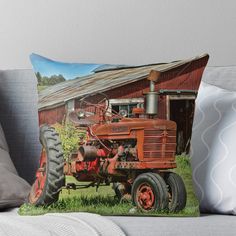 an old red tractor parked in front of a barn throw pillow