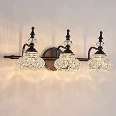 three light bathroom fixture with glass shades and metal fittings on the wall above it