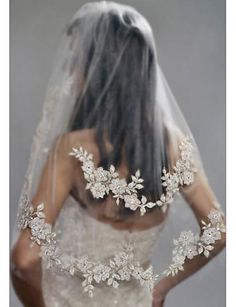 the back of a bride's wedding dress with flowers and pearls on her veil