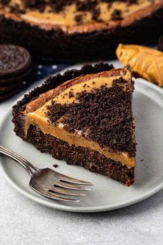 a piece of chocolate cake on a plate with a fork and oreo cookies in the background